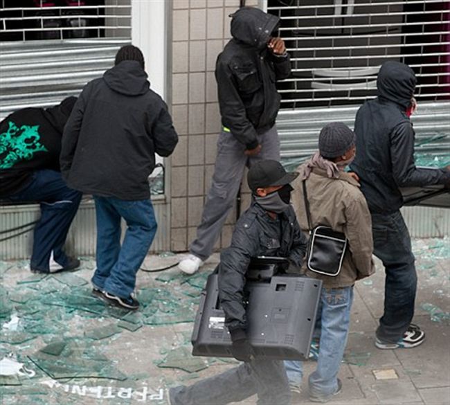 group youthsone carrying stolen television walks past shop Hackney